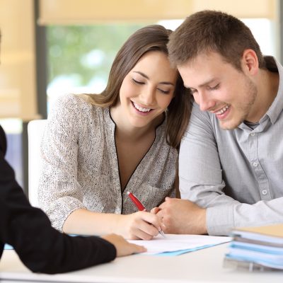 Happy couple signing a contract together at office